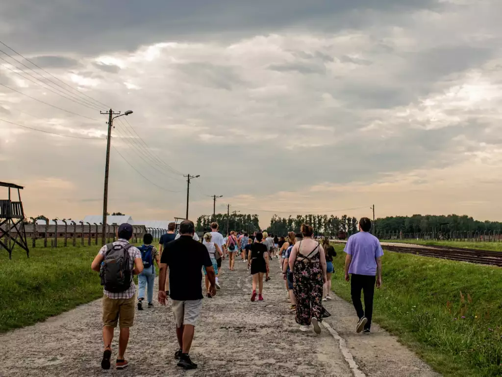 Group of tourists walking across the Auschwitz II Birkenau main path