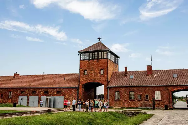 Auschwitz II train gate with a group of tourists standing next to it.